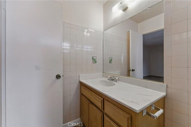 bathroom featuring vanity and tile walls