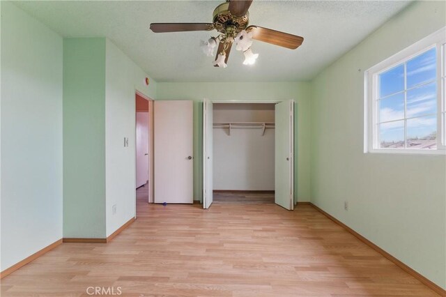 unfurnished bedroom featuring ceiling fan, baseboards, light wood-style floors, and a closet