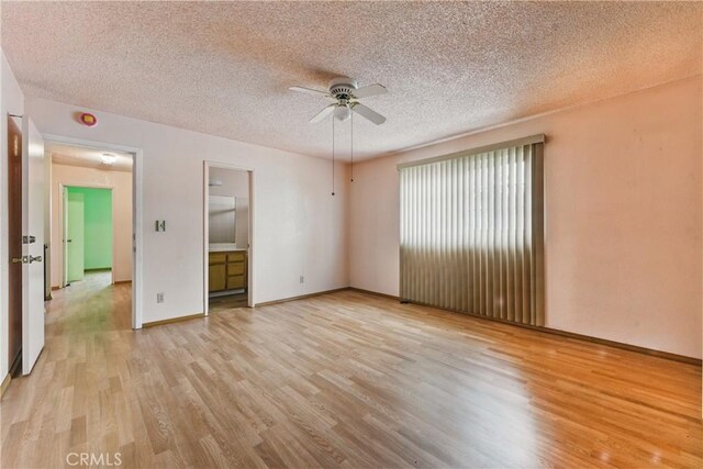 unfurnished bedroom with baseboards, a textured ceiling, and light wood-style flooring