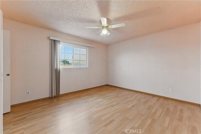 empty room featuring light wood-style flooring, a textured ceiling, a ceiling fan, and baseboards