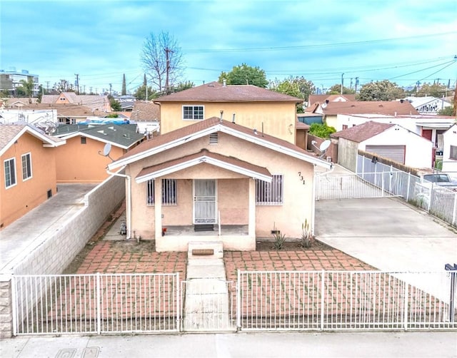 view of front facade featuring a residential view, a fenced front yard, a gate, a porch, and stucco siding
