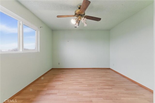 unfurnished room with light wood finished floors, baseboards, and a ceiling fan