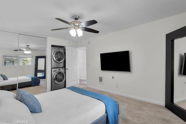 bedroom featuring baseboards, carpet flooring, stacked washer / dryer, and a closet