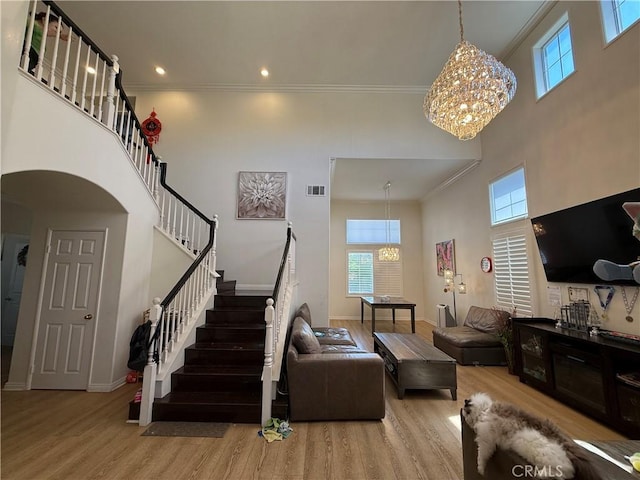 living area with a towering ceiling, a chandelier, and wood finished floors
