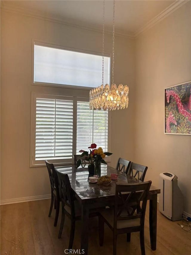 dining area featuring an inviting chandelier, ornamental molding, light wood-style flooring, and baseboards