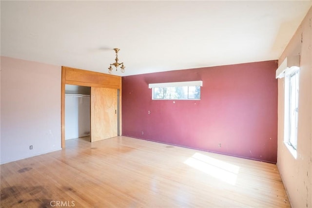 unfurnished bedroom with a closet, a notable chandelier, and light wood-style floors