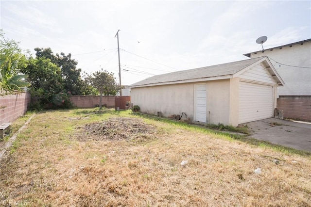 view of yard featuring a detached garage, fence, and an outdoor structure