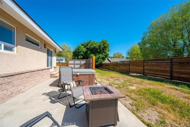 view of patio / terrace featuring a hot tub, a fenced backyard, and an outdoor fire pit