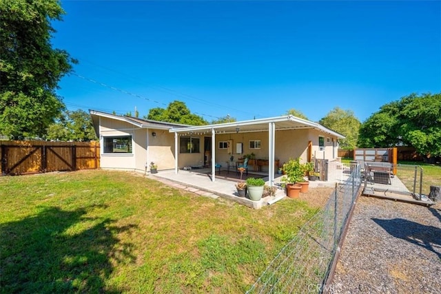 rear view of house with a lawn, a fenced backyard, and a patio area