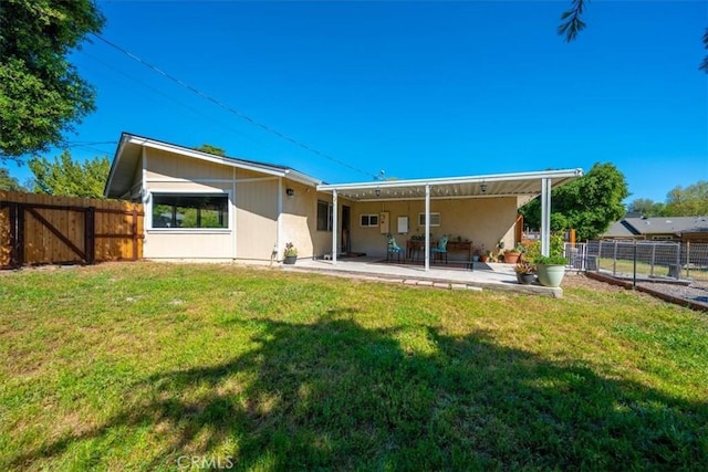 back of house featuring a lawn, a patio, and fence