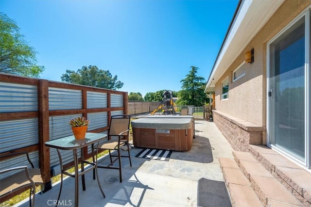 view of patio featuring a fenced backyard, a hot tub, and a playground
