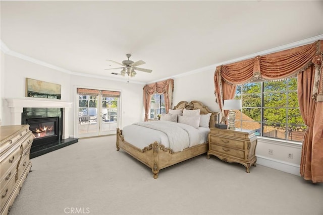 bedroom with crown molding, access to outside, light colored carpet, and a glass covered fireplace
