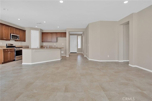18870 Stetson St, Apple Valley, CA 92308 - kitchen featuring appliances with stainless steel finishes, recessed lighting, open floor plan, light stone countertops, and a center island with sink