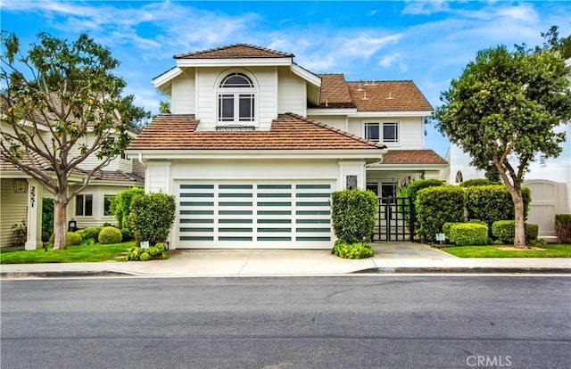 traditional-style house featuring a tiled roof, an attached garage, and driveway