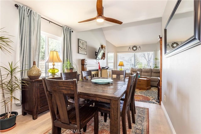 dining area featuring light wood-style floors, baseboards, ceiling fan, and lofted ceiling