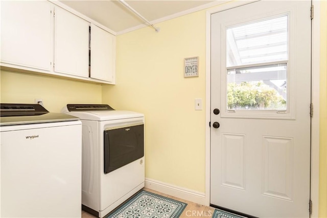 clothes washing area with separate washer and dryer, baseboards, and cabinet space