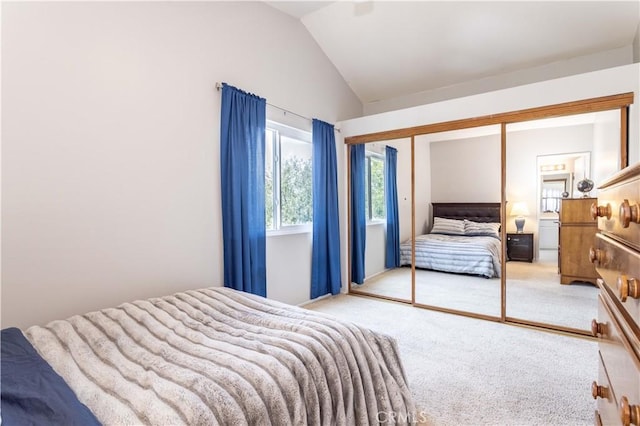 carpeted bedroom with a closet and lofted ceiling
