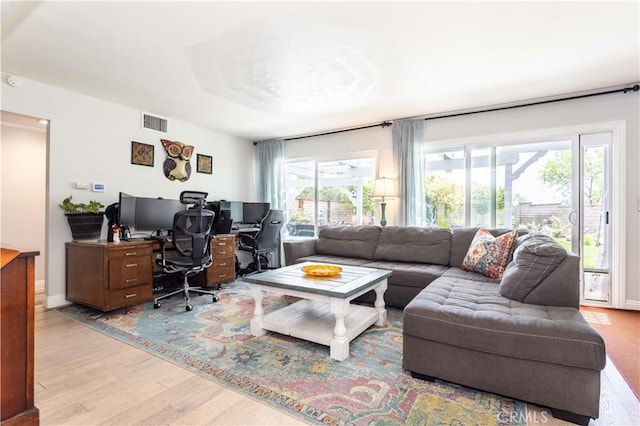 living area with visible vents, light wood finished floors, and a healthy amount of sunlight