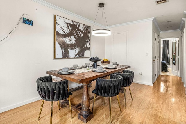 dining area featuring light wood-style floors, baseboards, and ornamental molding