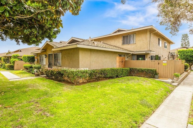 view of front of home featuring fence, a front lawn, and stucco siding