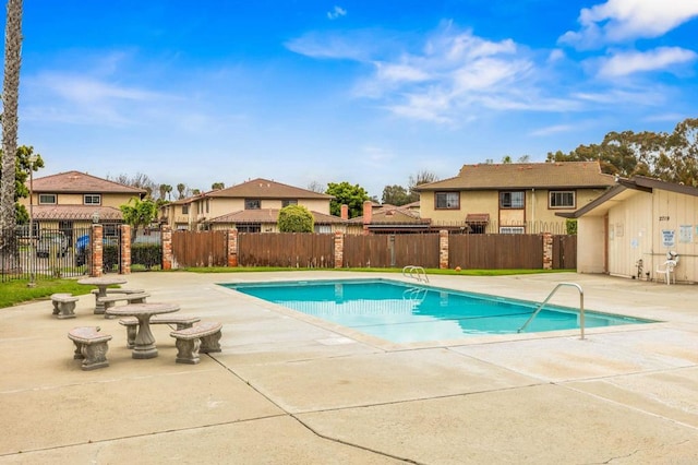 community pool featuring a residential view, a patio area, and fence