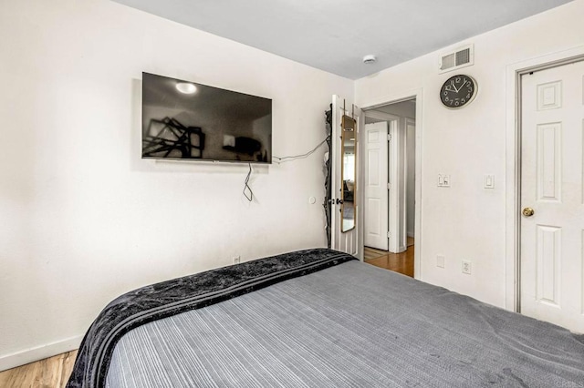 bedroom with baseboards, wood finished floors, and visible vents