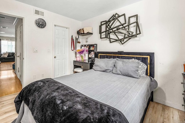 bedroom with wood finished floors, visible vents, and baseboards