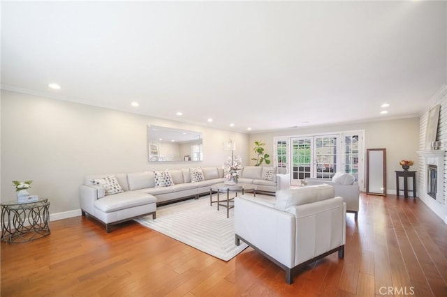 living room featuring hardwood / wood-style floors, recessed lighting, ornamental molding, and baseboards