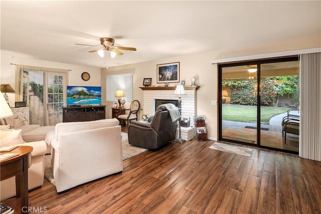 living area featuring ceiling fan, baseboards, wood finished floors, and a fireplace