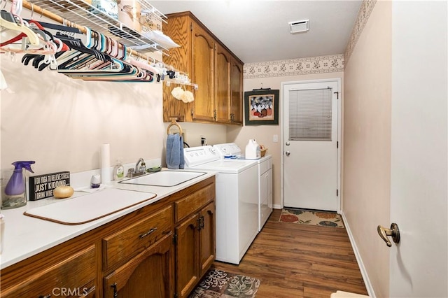 laundry area featuring a sink, separate washer and dryer, cabinet space, baseboards, and dark wood-style floors