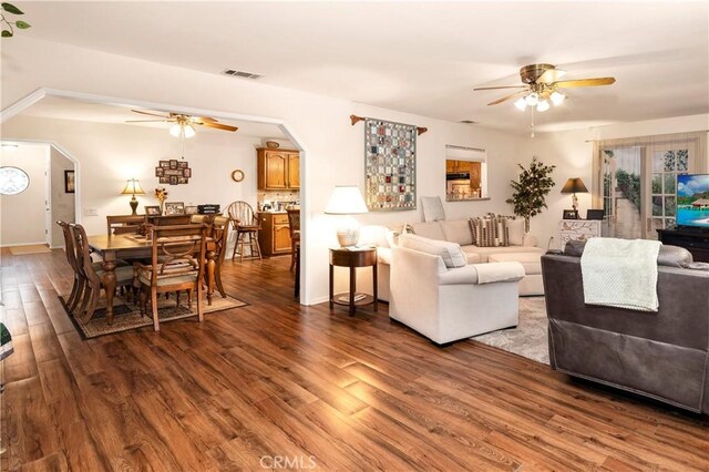 living area featuring arched walkways, wood finished floors, visible vents, and a ceiling fan