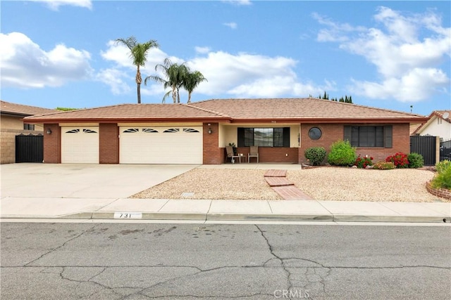 ranch-style home with concrete driveway, an attached garage, brick siding, and fence