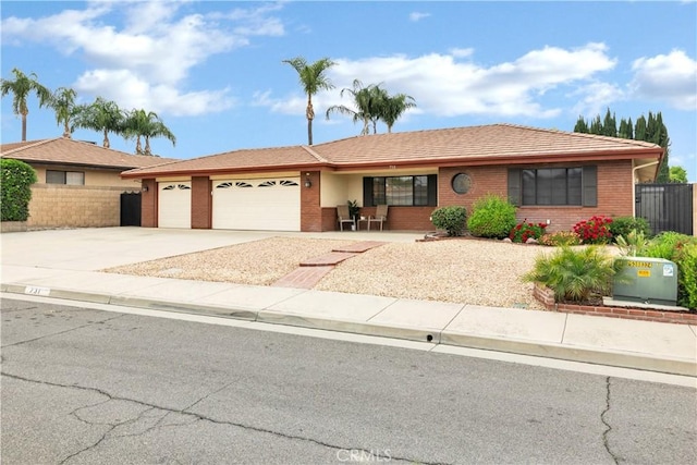 ranch-style home with concrete driveway, an attached garage, brick siding, and fence