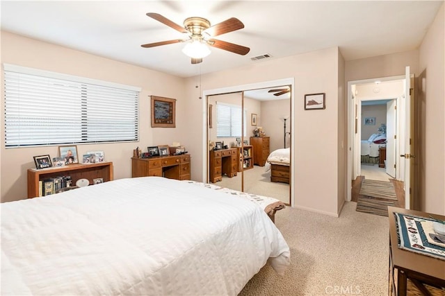 bedroom with a closet, visible vents, a ceiling fan, and light carpet