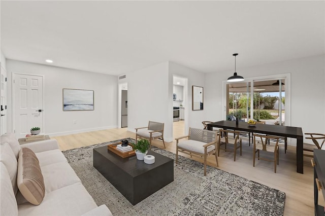 living area with light wood-style floors, visible vents, and recessed lighting