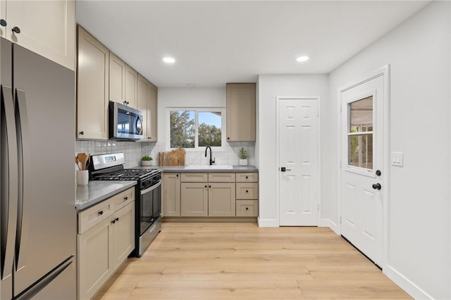 kitchen featuring a sink, light wood-type flooring, backsplash, appliances with stainless steel finishes, and recessed lighting