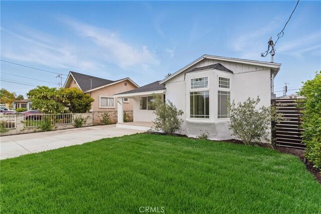 view of front of house featuring fence, a patio, a front yard, and stucco siding