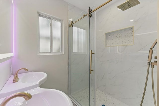 bathroom with a marble finish shower and a sink
