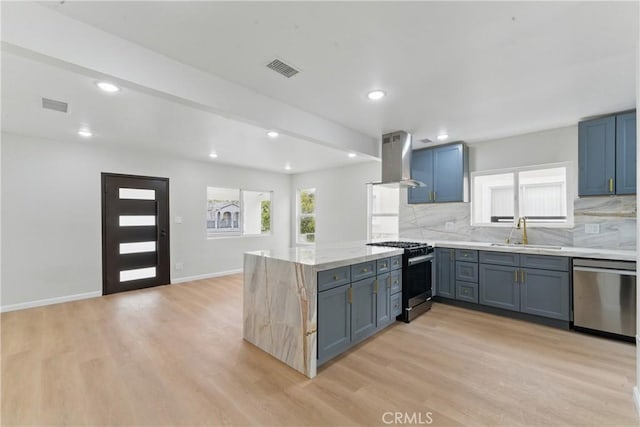 kitchen featuring light wood-style floors, island exhaust hood, appliances with stainless steel finishes, and a sink