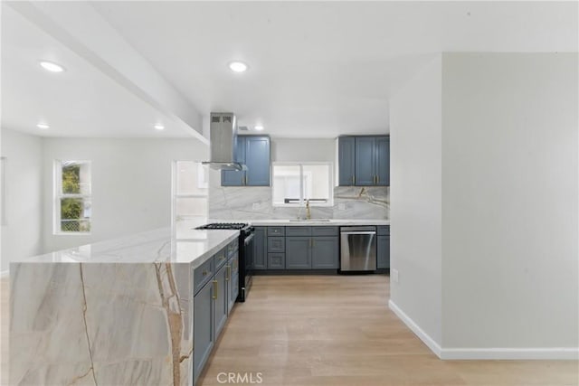 kitchen with a sink, light wood-type flooring, backsplash, island range hood, and appliances with stainless steel finishes