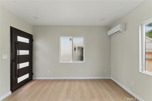 entrance foyer featuring baseboards, light wood-style floors, and a wall mounted air conditioner