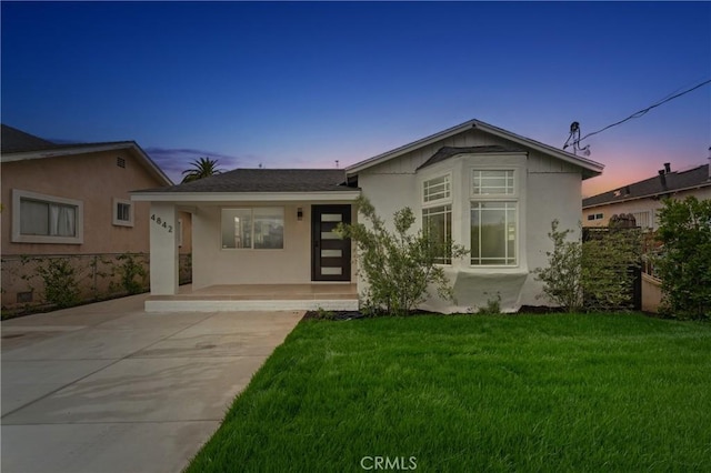ranch-style house with a front lawn, covered porch, and stucco siding