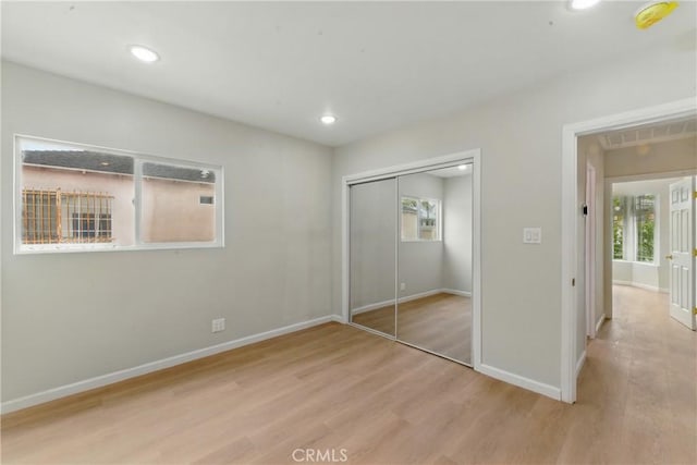 unfurnished bedroom featuring wood finished floors, visible vents, baseboards, and multiple windows