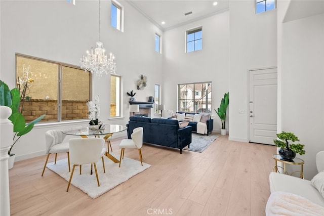 interior space featuring a high ceiling, visible vents, ornamental molding, light wood-type flooring, and a notable chandelier