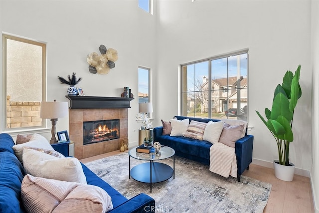 living area featuring a tile fireplace, wood finished floors, and a wealth of natural light