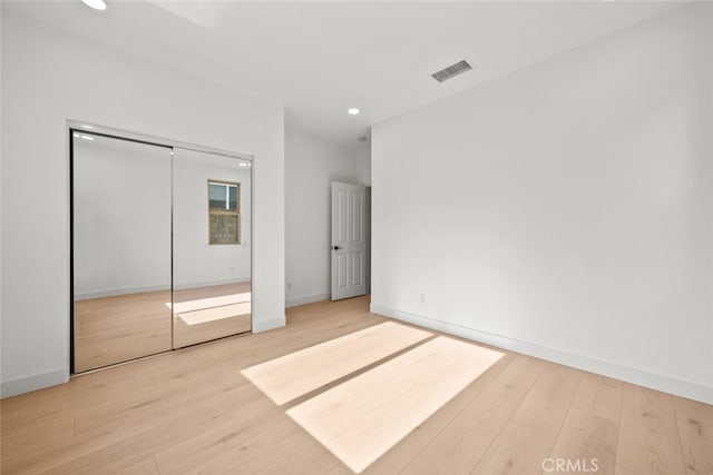 unfurnished bedroom with baseboards, wood finished floors, visible vents, and recessed lighting