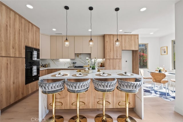 kitchen with a kitchen breakfast bar, tasteful backsplash, recessed lighting, modern cabinets, and light countertops