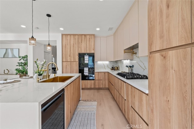kitchen with a sink, black appliances, light wood-style floors, modern cabinets, and visible vents