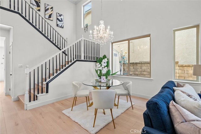 dining space with stairway, a chandelier, wood finished floors, and a towering ceiling
