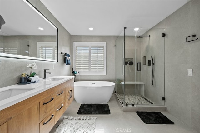 full bath with double vanity, a freestanding tub, a stall shower, and a sink